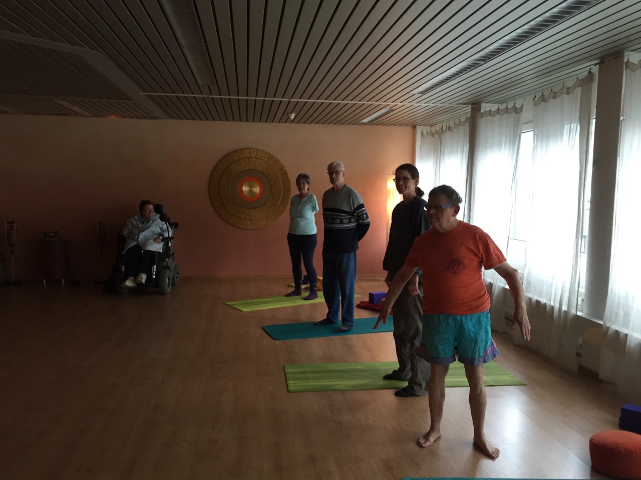 Das Foto zeigt Aktivmitglieder von Procap Luzern, Ob- und Nidwalden in einem Yogastudio in Luzern beim Yoga. Das Foto ist eher dunkel. Es wird versucht mit wenig Licht eine wohlige und entspannte Atmosphäre im Raum zu erreichen.