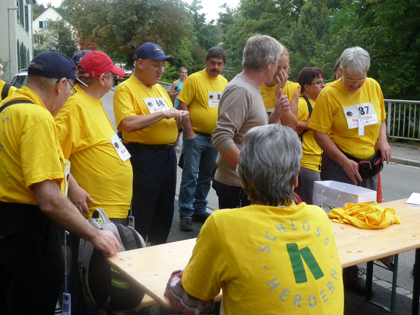 Auf dem Foto sieht man 9 Bewohner und Mitarbeiter vom Schloss Herdern. Sie sind in der Vorbereitung zum 2-Stunden Sponsorenlauf in Frauenfeld.Alle tragen ein gelbes Tshirt mit dem Aufdruck: 